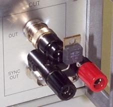 The photograph shows a 1 Ohm test load (a high-power, low-inductance, Caddock MP821-1.0-1% resistor in a TO-220 package) installed on a BNC-to-post adapter (Pomona model 1296). The adapter connects directly to the BNC 